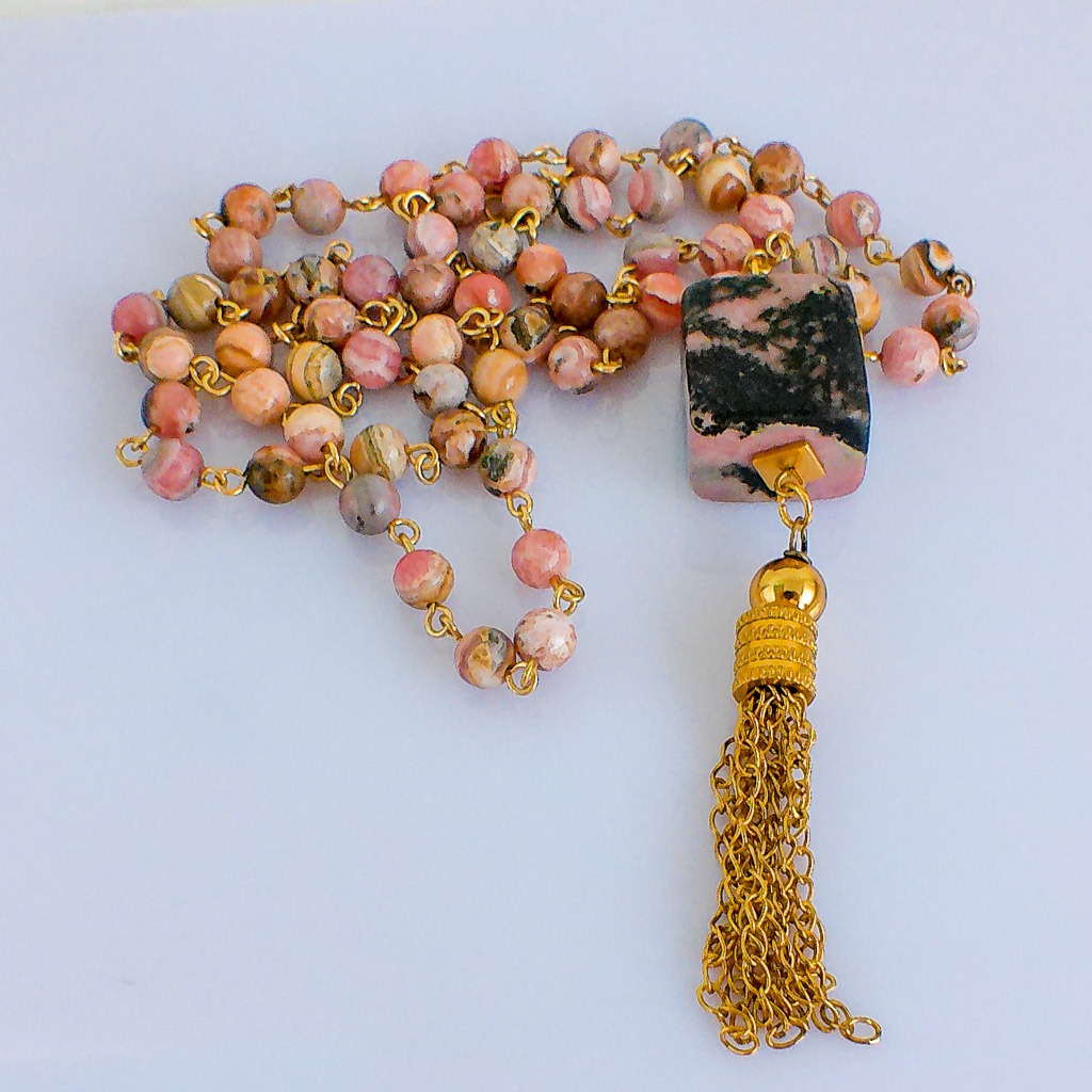 Material: Cubo de Rodonita con cuentas naturales de Rodonita, hilo y fornituras de acero inoxidable bañado en oro. Longitud collar: 84 cm. Dimensión piedra: 2 x 2 cm. Propiedades de la piedra: Piedra calmante que reduce la ansiedad, indicada contra miedos excesivos y angustia. Para superar momentos difíciles y traumas. Alivia confusión, elimina somatizaciones, cura shocks emocionales, calma y reconforta. Curación de vidas pasadas y de emociones difíciles. Limpia y cicatriza las heridas emocionales. Elemento: Agua. Emociones, deseos, curación, liberación, fluidez, avance. *Las piedras semipreciosas pueden variar ligeramente de tono y forma debido a su origen natural*
