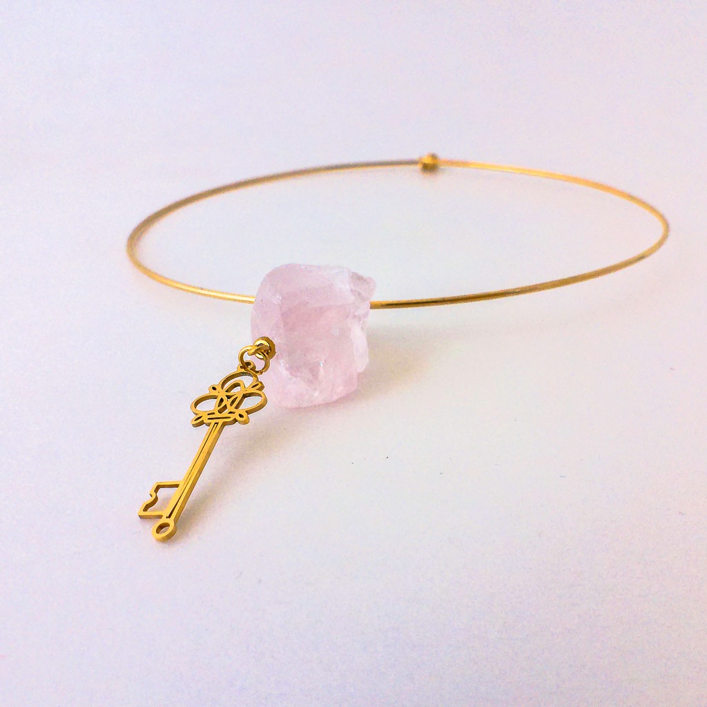 Material: Piedra natural en bruto de Cuarzo Rosa con gargantilla rígida y colgante Llave de acero inoxidable. Longitud cadena: 45 cm. Dimensión piedra: 2,5 x 2 cm. Dimensión colgante: 3,5 x 1 cm. Significado: Cuarzo Rosa, piedra por excelencia de los sentimientos unida al símbolo de la llave asociado al control emocional y poder de acceso a nuestro interior. Propiedades de la piedra: Burbuja de amor y ternura. Piedra de amor incondicional y paz infinita. Aporta seguridad y calma. Mejora la autoestima, elimina miedos, inspira, apacigua y sana emociones. Sedante y relajante. Desbloquea el chakra corazón. Curación profunda. Transmite calidez y amor. Elemento: Agua. Emociones, deseos, curación, liberación, fluidez, avance *las piedras semipreciosas pueden variar ligeramente de tono y forma debido a su origen natural*