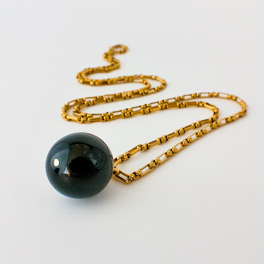 Material: Piedra natural esfera de Obsidiana Negra con cadena caja redonda y fornituras de acero inoxidable bañado en oro. Longitud collar: 80 cm. Dimensión piedra: 1,5 x 1,5 cm. Propiedades de la piedra: Considerada piedra sin fronteras ni limitaciones, tiene un poder vibratorio muy fuerte. Actúa como catarsis, saca a la luz todo lo que llevamos escondido, abre y cierra heridas para poder transformarnos y crecer a todos los niveles. Absorbe todo tipo de energías negativas y geopáticas, gran escudo protector. Ayuda a vitalizar el propósito de tu alma. Utilizada desde la antigüedad como bola de adivinación, anima a explorar lo desconocido, comunicación con mundos paralelos y viajes astrales. Multiplica por diez tu fuerza mental y ayuda a tomar decisiones difíciles. Piedra de cambios. Elemento: Tierra. Estabilidad, seguridad, equilibrio, abundancia y protección. *Las piedras semipreciosas pueden variar ligeramente de tono y forma debido a su origen natural*