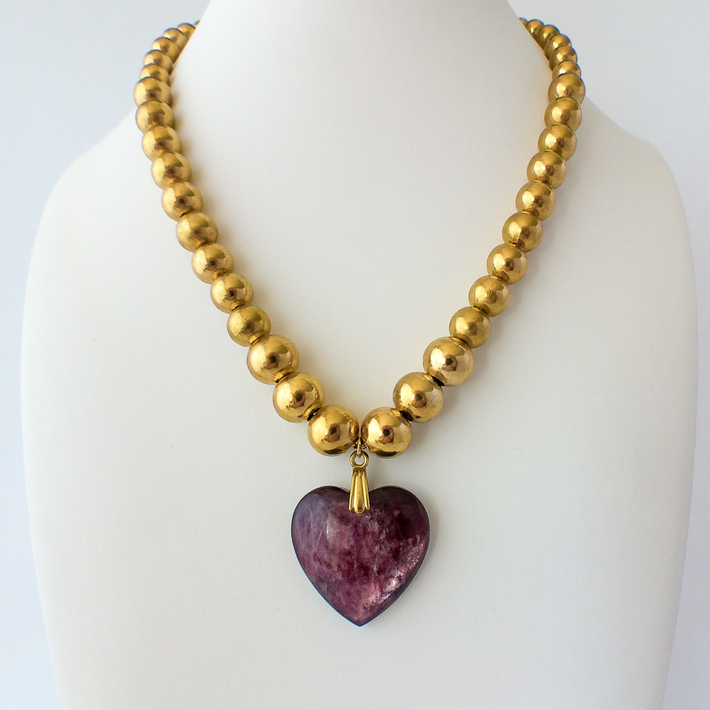 Material: Cadena de bolas grandes de acero inoxidable con piedra en forma de corazón de Lepidolita. Diámetro de la cadena: 14 cm. Tamaño de la piedra: 3 x 3 cm. Propiedades de la piedra: Proporciona calma, templanza y confianza en uno mismo. Debido a su alto contenido en litio está indicada contra la tristeza, depresión, ansiedad, miedo y cualquier trastorno psicológico. Ofrece protección y hace salir tu yo superior. Disipa bloqueos. Piedra de transición que libera y reorganiza viejos patrones psicológicos de conducta. Elemento: Agua. Emociones, deseos, curación, liberación, fluidez, avance. *Las piedras semipreciosas pueden variar ligeramente de tono y forma debido a su origen natural*