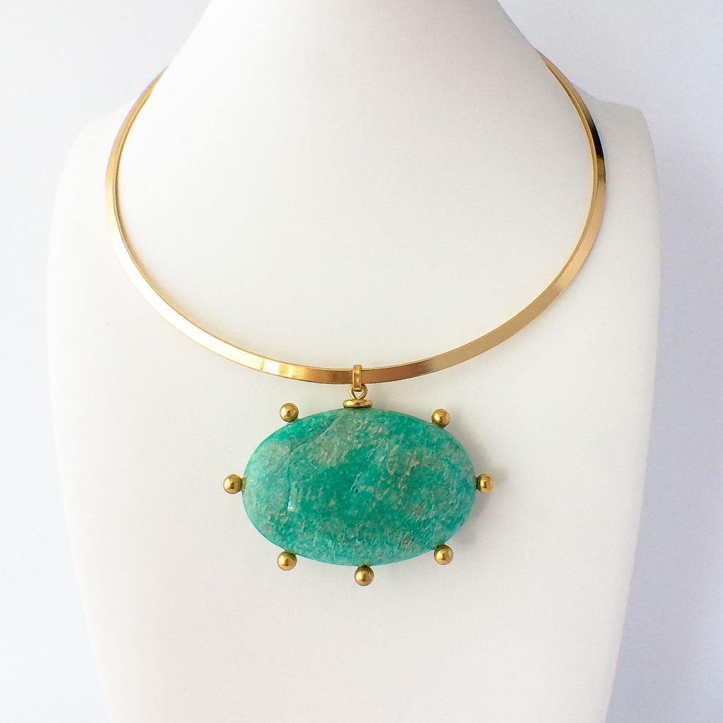 Material: Choker rígido de acero inoxidable con óvalo de Amazonita con incrustaciones de bolas. Tamaño de la piedra: 6 x 4 cm. Diámetro del collar: 15 cm. Propiedades de la piedra: Piedra calmante de vibración muy suave que elimina la tristeza y proporciona alivio, calma, serenidad, felicidad y equilibrio emocional. Abosbe ondas electromagnéticas y bloquea las tensiones y la contaminación de cualquier tipo. Simboliza el refugio el alivio. Elemento Aire: Espiritualidad, pensamiento, pureza, libertad, renovación. *Las piedras semipreciosas pueden variar ligeramente de tono y forma debido a su origen natural*