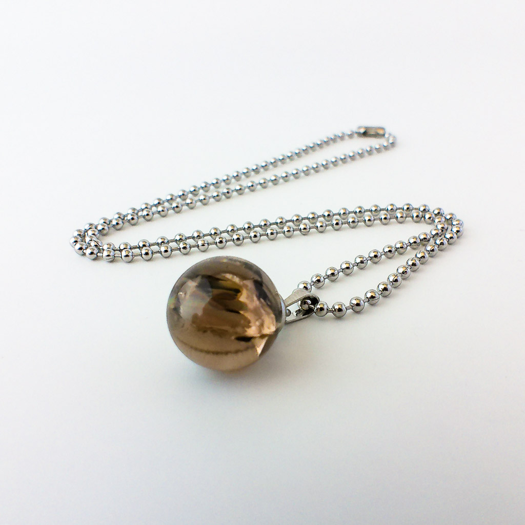 Material: Esfera de Cuarzo Ahumado con cadena de acero inoxidable. Tamaño de la piedra: 15mm. Largura: 25 cm. Propiedades de la piedra: Canaliza la luz del universo en el plano físico. Ayuda a disolver cualquier tipo de energía densa. Calma las emociones difíciles. Proporciona sabiduría y pensamiento claro. Es un antídoto contra el estrés y transmite positividad. Elemento Tierra: Estabilidad, seguridad, equilibrio, abundancia y protección. *Las piedras semipreciosas pueden variar ligeramente de tono y forma debido a su origen natural*